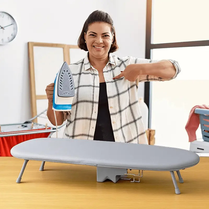 Woman holding an iron next to LivinH Foldable Ironing Board in a home setting.